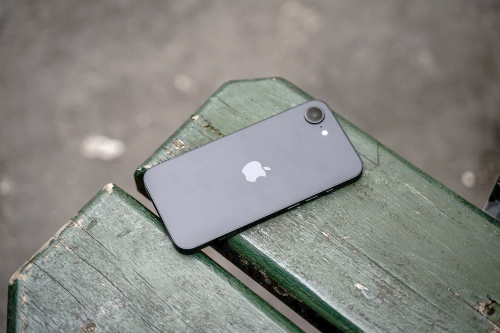 iPhone 16e noir posé sur un banc dos min